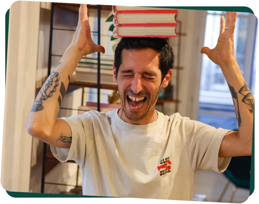 Photo de Guillaume, directeur création, en train de faire tenir des livres en équilibres sur sa tête les yeux fermés