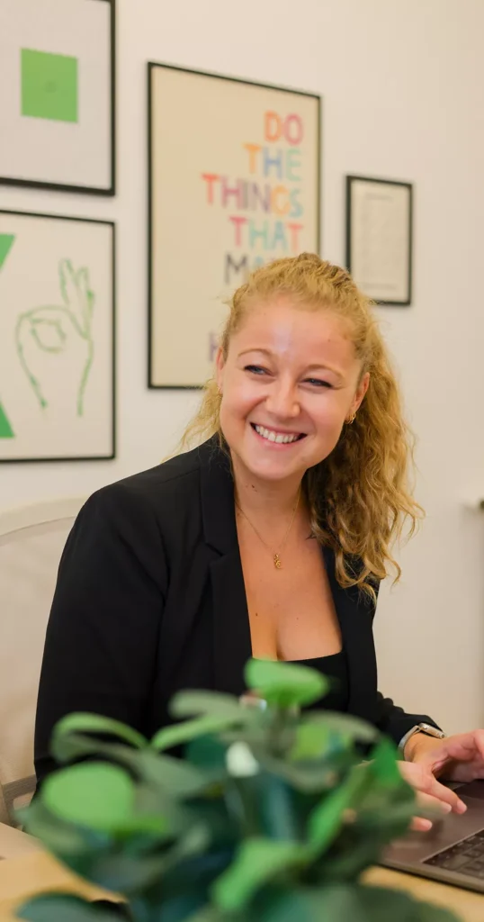 Photo de Pauline, fondatrice de l'agence HKM en train de sourire à son interlocuteur en travaillant à son poste