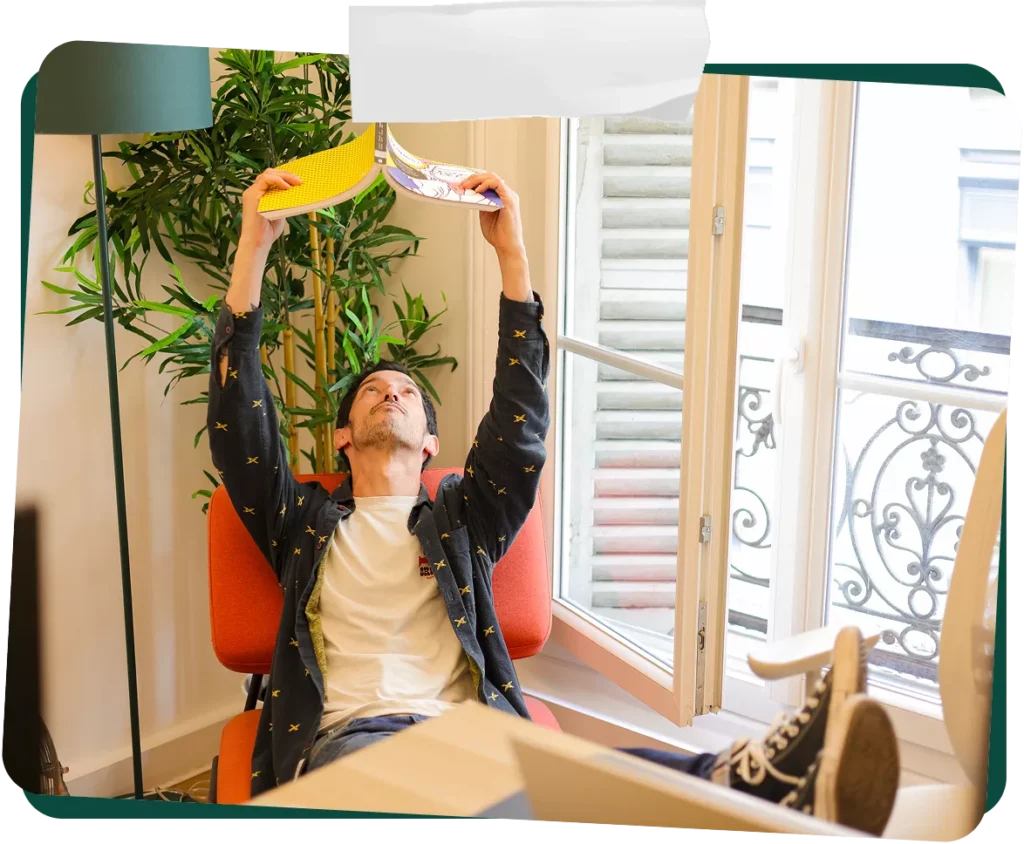 Photo de Guillaume, directeur de création, en train de lire un livre au dessus de sa tête dans le bureau